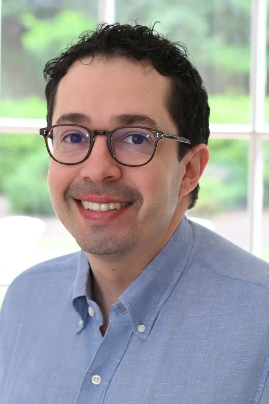 Avi Swerdlow wearing glasses and a blue shirt.